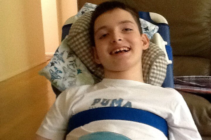 Harrison Creevey smiles at the camera reclining in chair.