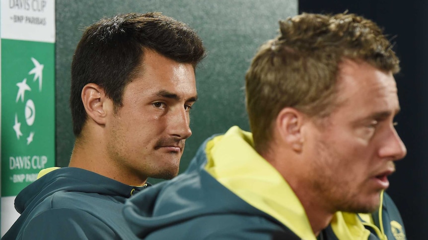 Bernard Tomic looks at Lleyton Hewitt as he speaks during a Davis Cup press conference. Nick Kyrgios is sitting nearby.
