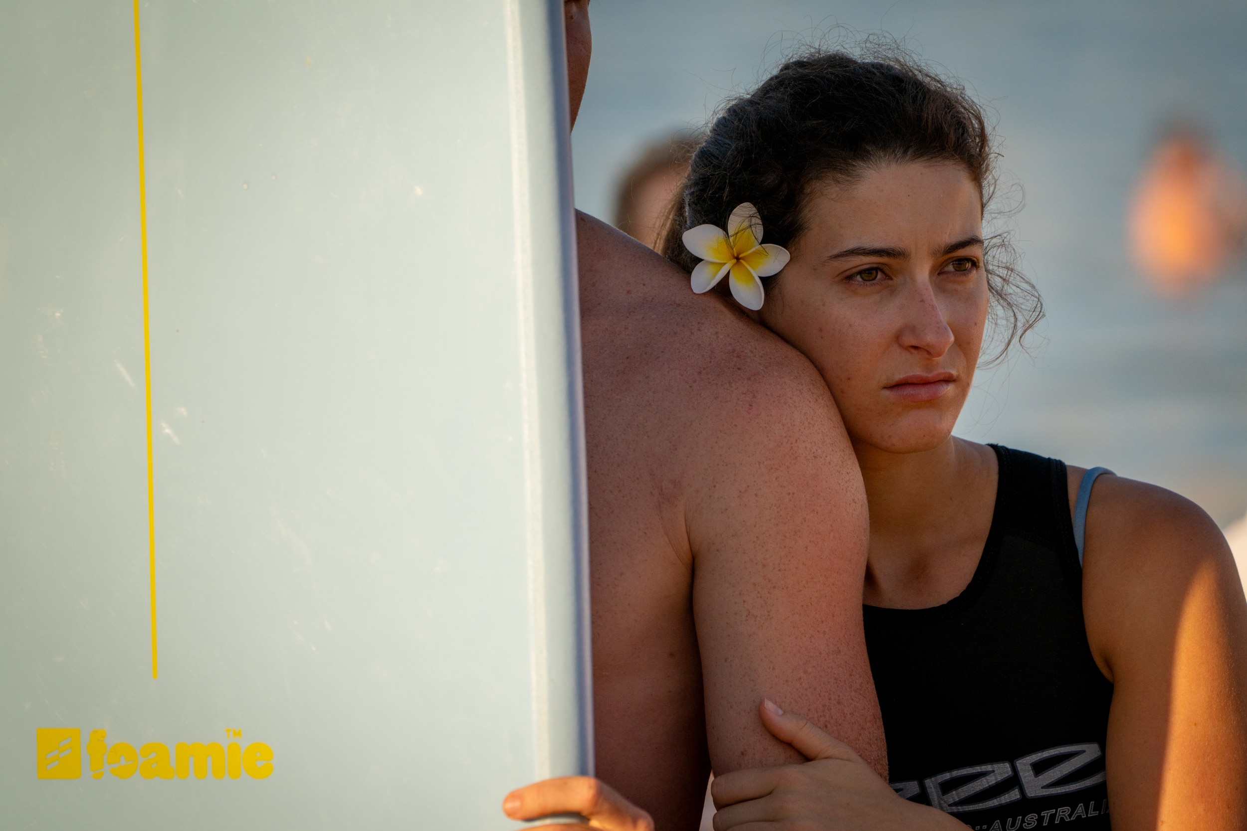 Una señora se para junto a una tabla de surf y observa con tristeza a Bondi remar.