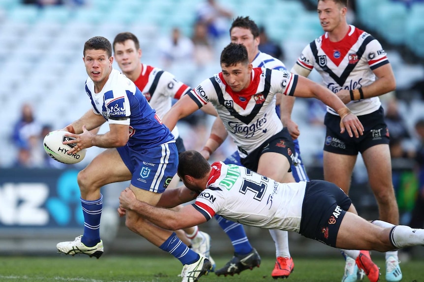 jack cogger is grabbed by a Sydney Roosters player as other players pursue him