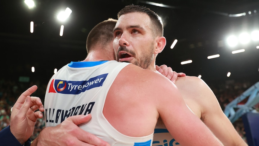 Two Melbourne United basketballers embrace mid-court after winning a game in the NBL finals series.