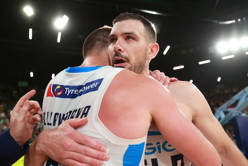 Two Melbourne United basketballers embrace mid-court after winning a game in the NBL finals series.