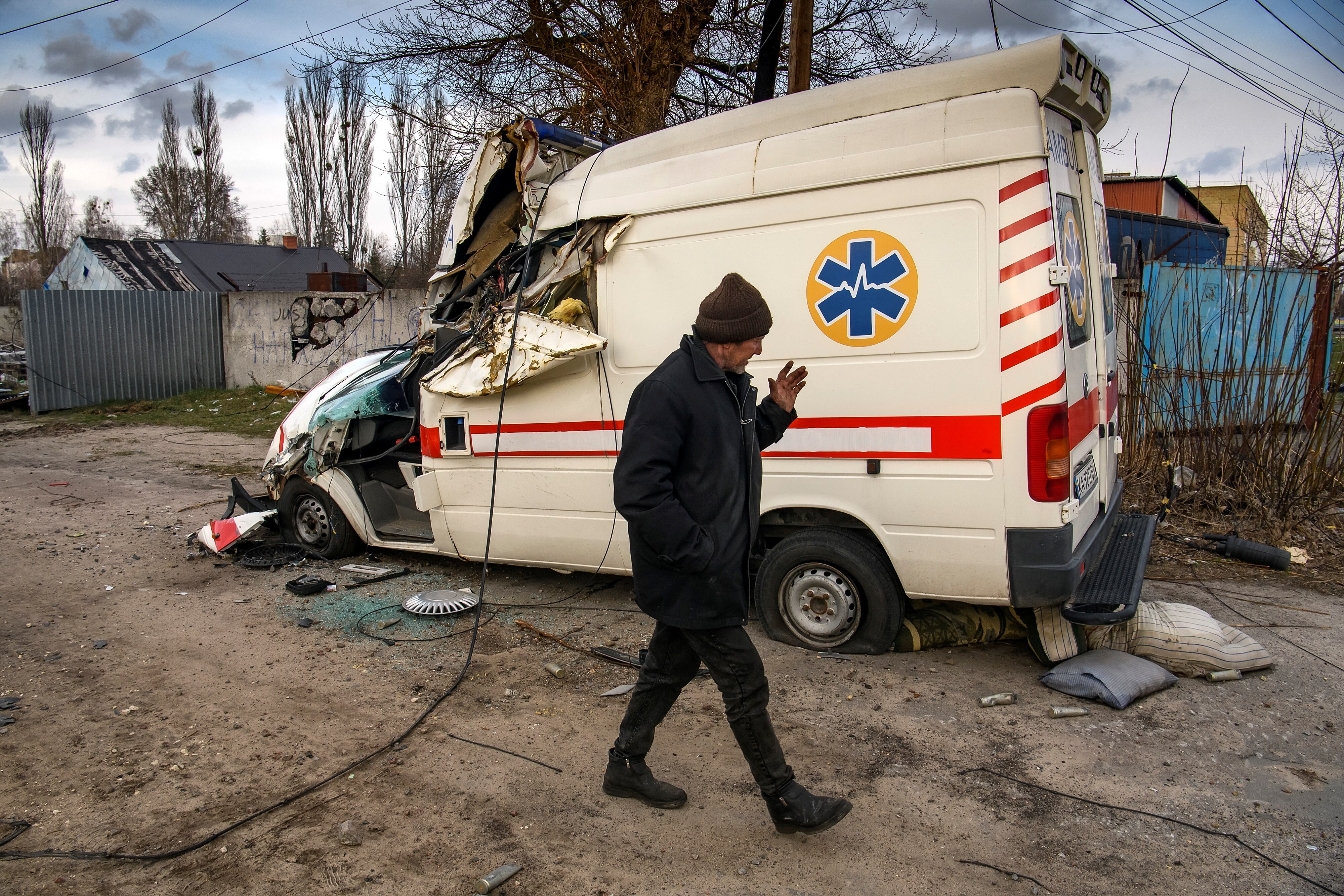 A man walks past a damaged ambulance.