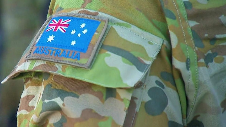 A close-up of an Australian Army patch and an Australian flag patch on an ADF officer's uniform.