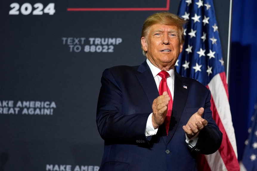 Former president Donald Trump claps his hand together at rally in Manchester, New Hampshire.