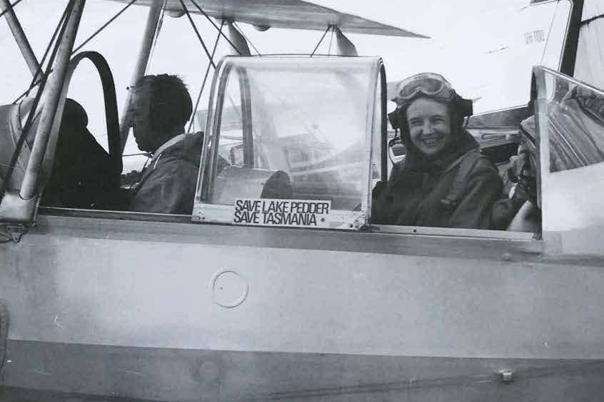 Old black and white photo of a woman smiling from a small plane.