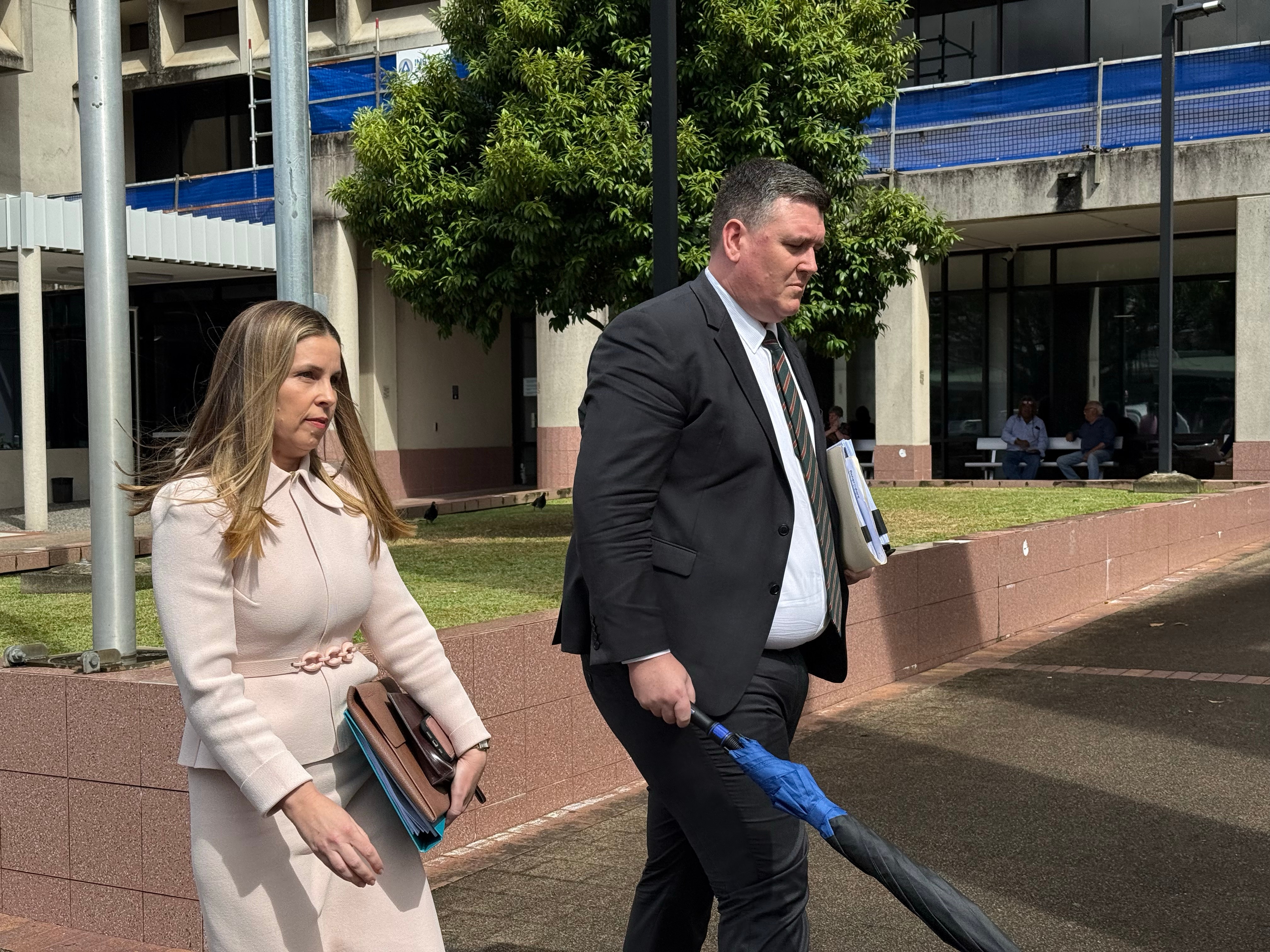 A woman and man in suits leave a court house. 