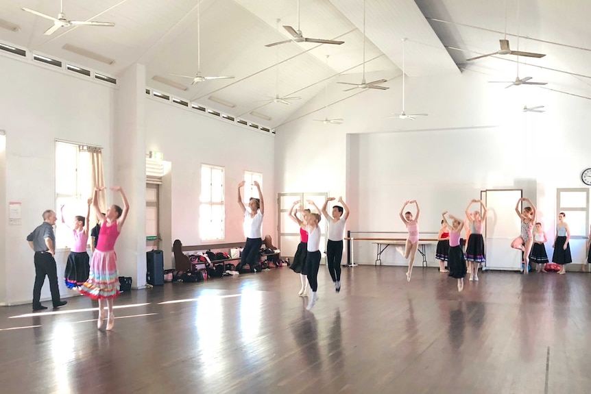 A group of ballerinas dancing in a hall room.