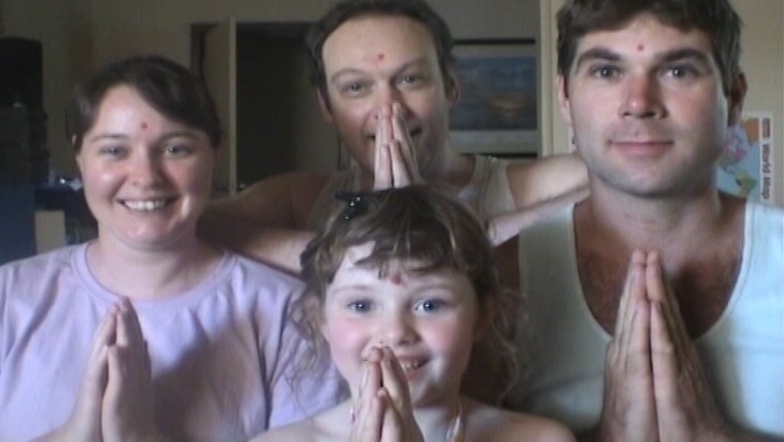 Two men, a woman and a child holding their hands in a prayer pose.