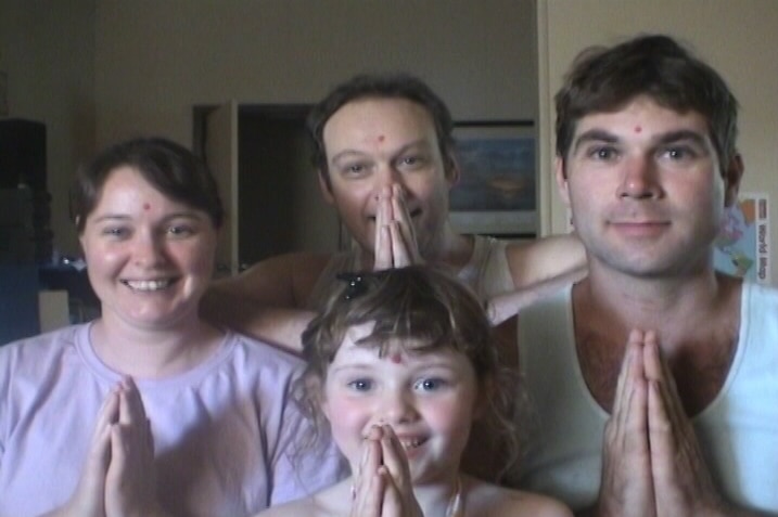 Two men, a woman and a child holding their hands in a prayer pose.