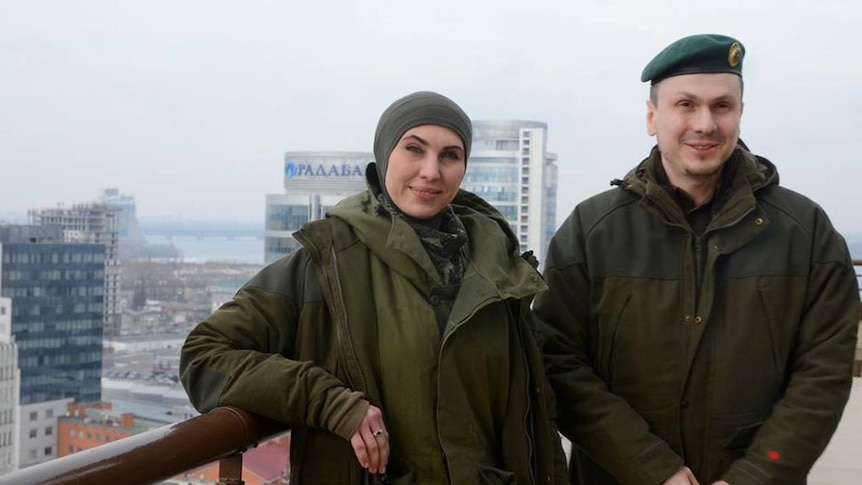 Amina Okuyeva and Adam Osmayev pose together on a balcony.