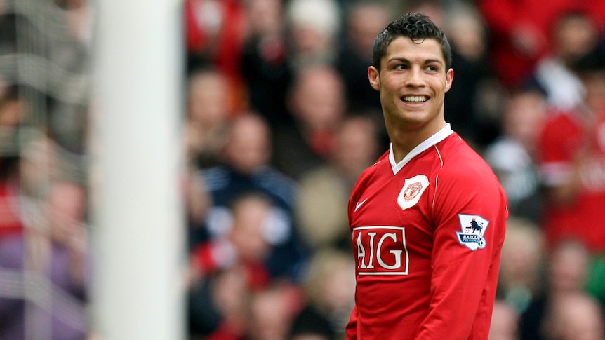 Cristiano Ronaldo gives a big smile as he stands on the pitch at Old Trafford in his Manchester United gear during a game.