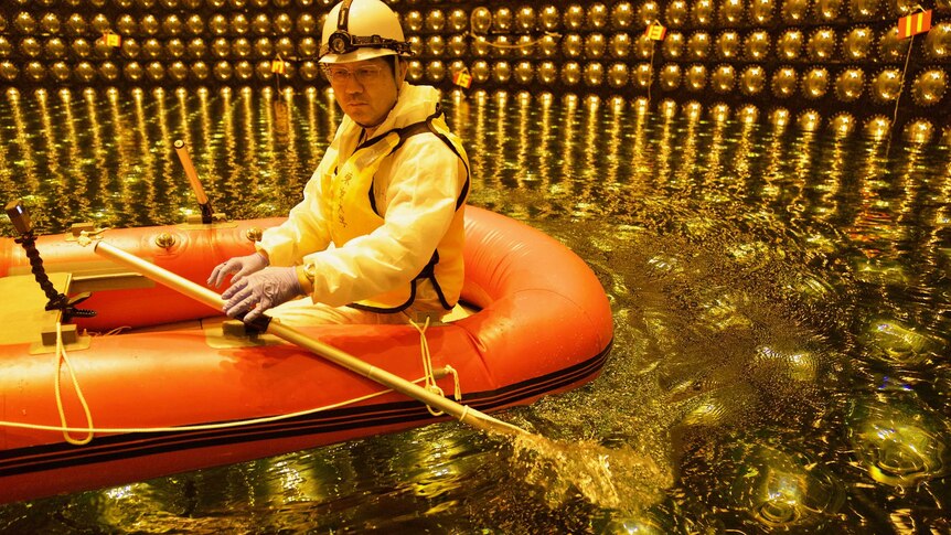 A Japanese scientist in a rubber boat in shallow water inside Super Kamiokande tank