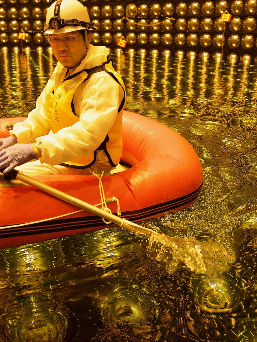 A Japanese scientist in a rubber boat in shallow water inside Super Kamiokande tank