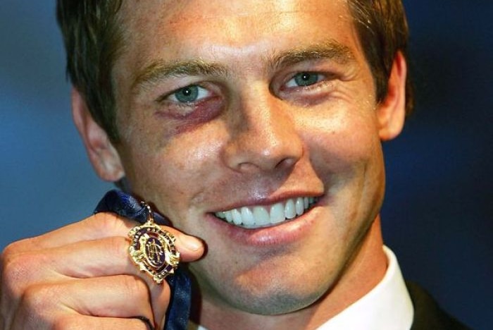 Ben Cousins smiles holding up a Brownlow Medal.