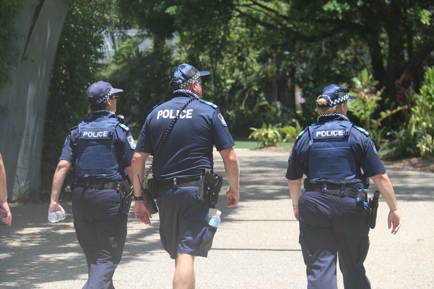 Uniformed police walk through South Bank. They are carrying water bottles and wearing caps.