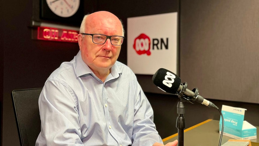 George Brandis in studio with RN sign at the back