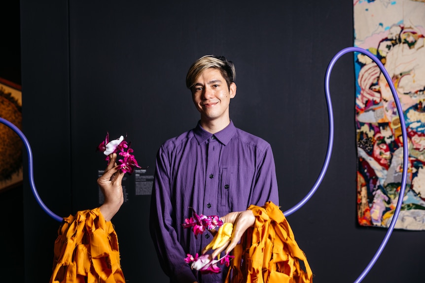 Nathan Beard stands behind his Ramsay Art Prize entry, a sculpture of a pair of hands holding flowers