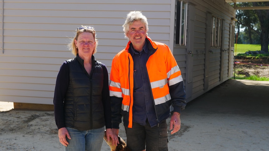 A smiling couple outside a farm shed.