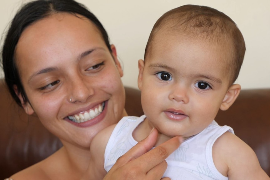 A gorgeous Tongan mother and her cute baby smiling, close up portrait.