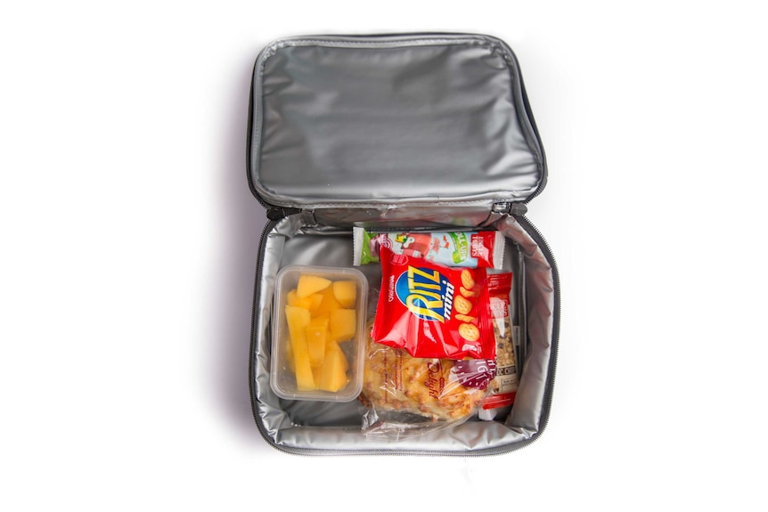 A cheese and bacon roll, chopped mango, a fruit roll-up, crackers and a choc chip muesli bar in a lunch cooler bag.