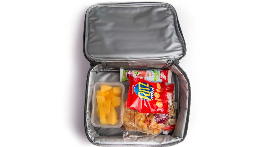 A cheese and bacon roll, chopped mango, a fruit roll-up, crackers and a choc chip muesli bar in a lunch cooler bag.