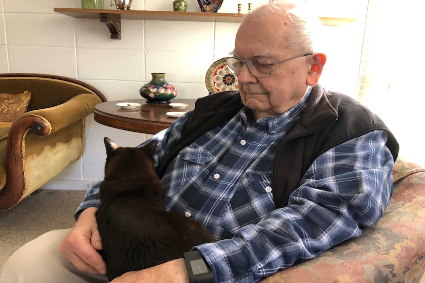 A black cat sits in Mike Saclier's lap.