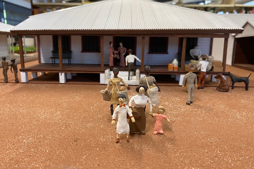 Miniature figurines outside a small building
