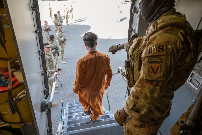 An Afghan civilian walks off a plane with US soldiers on the runway