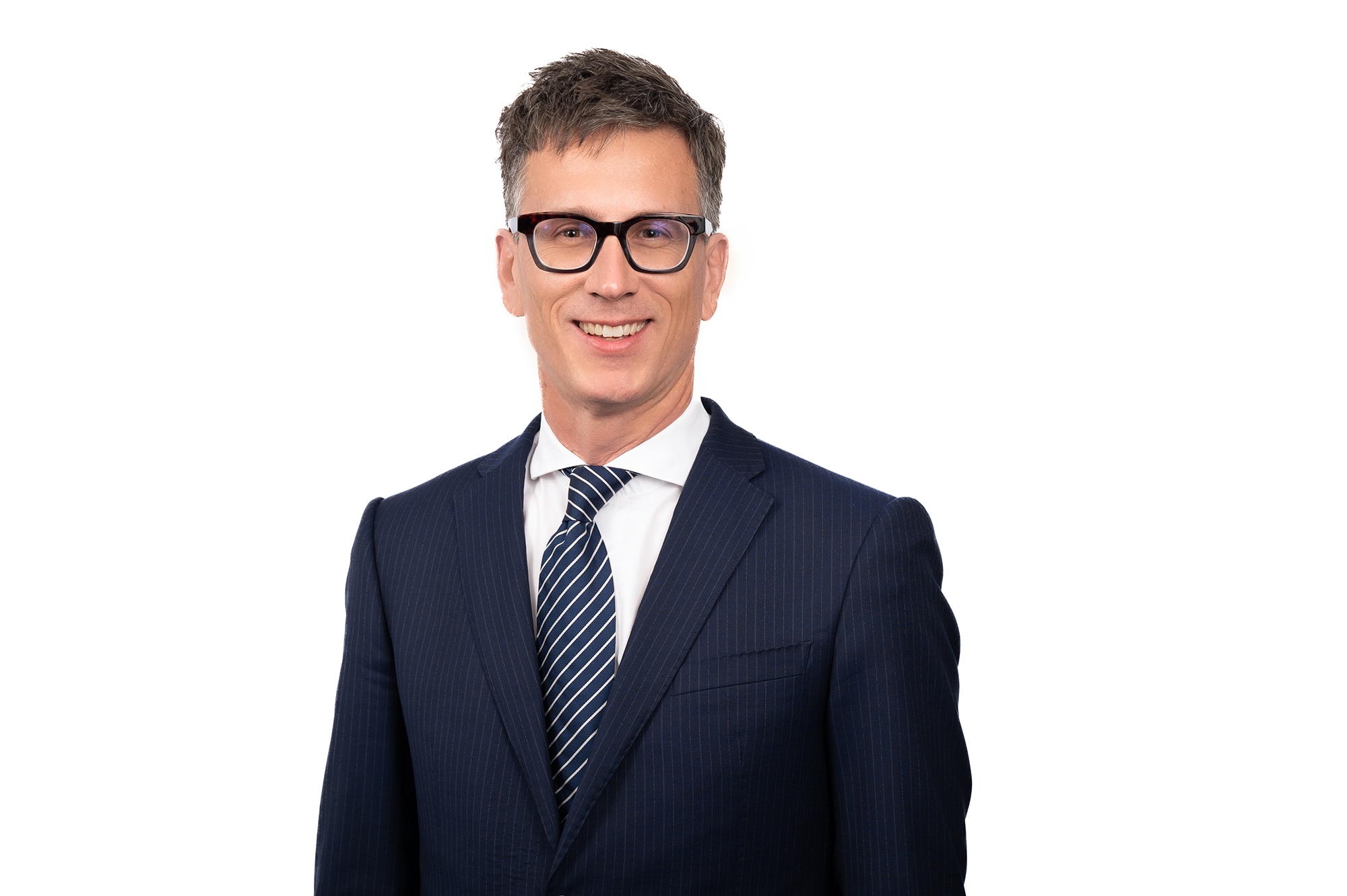 A smiling, dark-haired man in glasses and a suit.