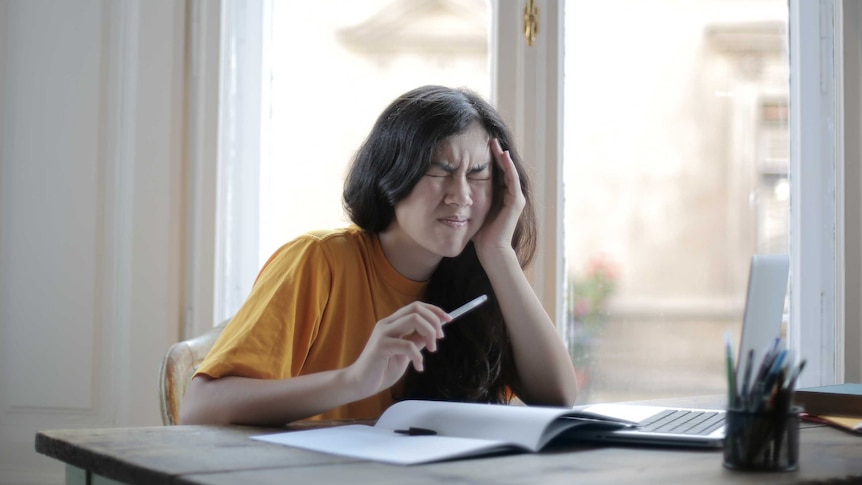 A woman looks visibly confused as she sits at her desk working with her computer.