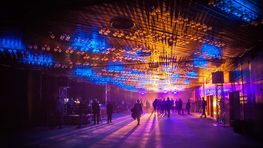 Inside a music venue lit up by coloured lights.