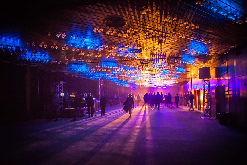 Inside a music venue lit up by coloured lights.