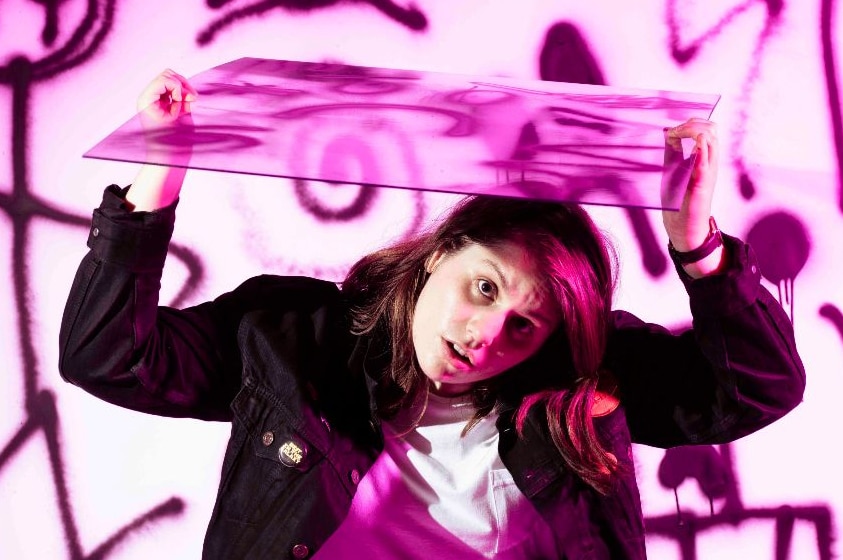 Melbourne musician Alex Lahey holds a pane of glass above her head