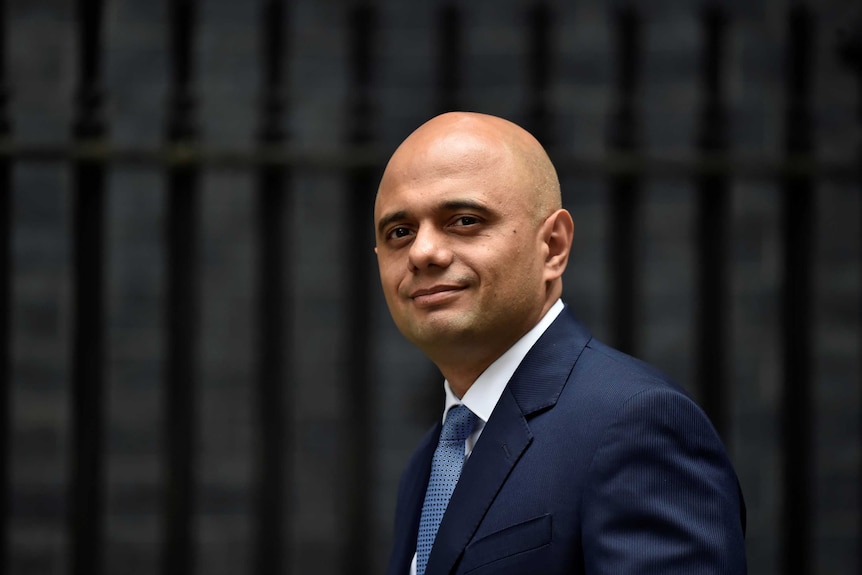 Sajid Javid stands outside with the blurred background of Downing Street behind him.