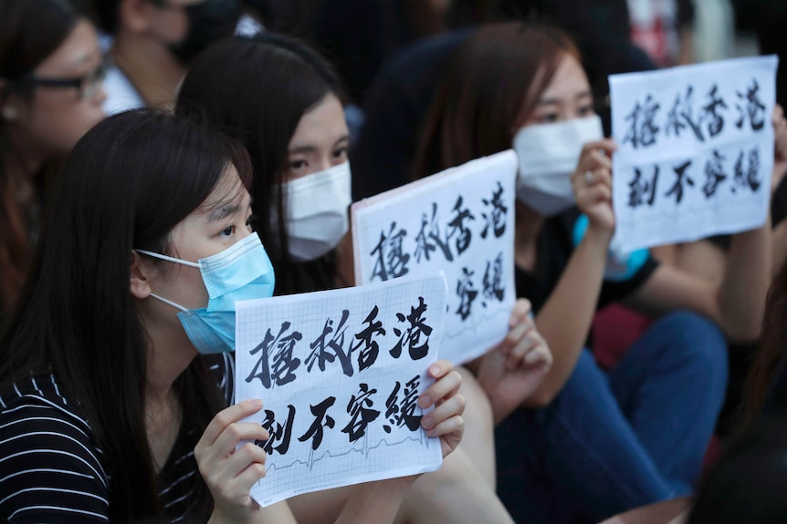 Protesters hold up signs that read "Rescue Hong Kong, There is no time for delay"