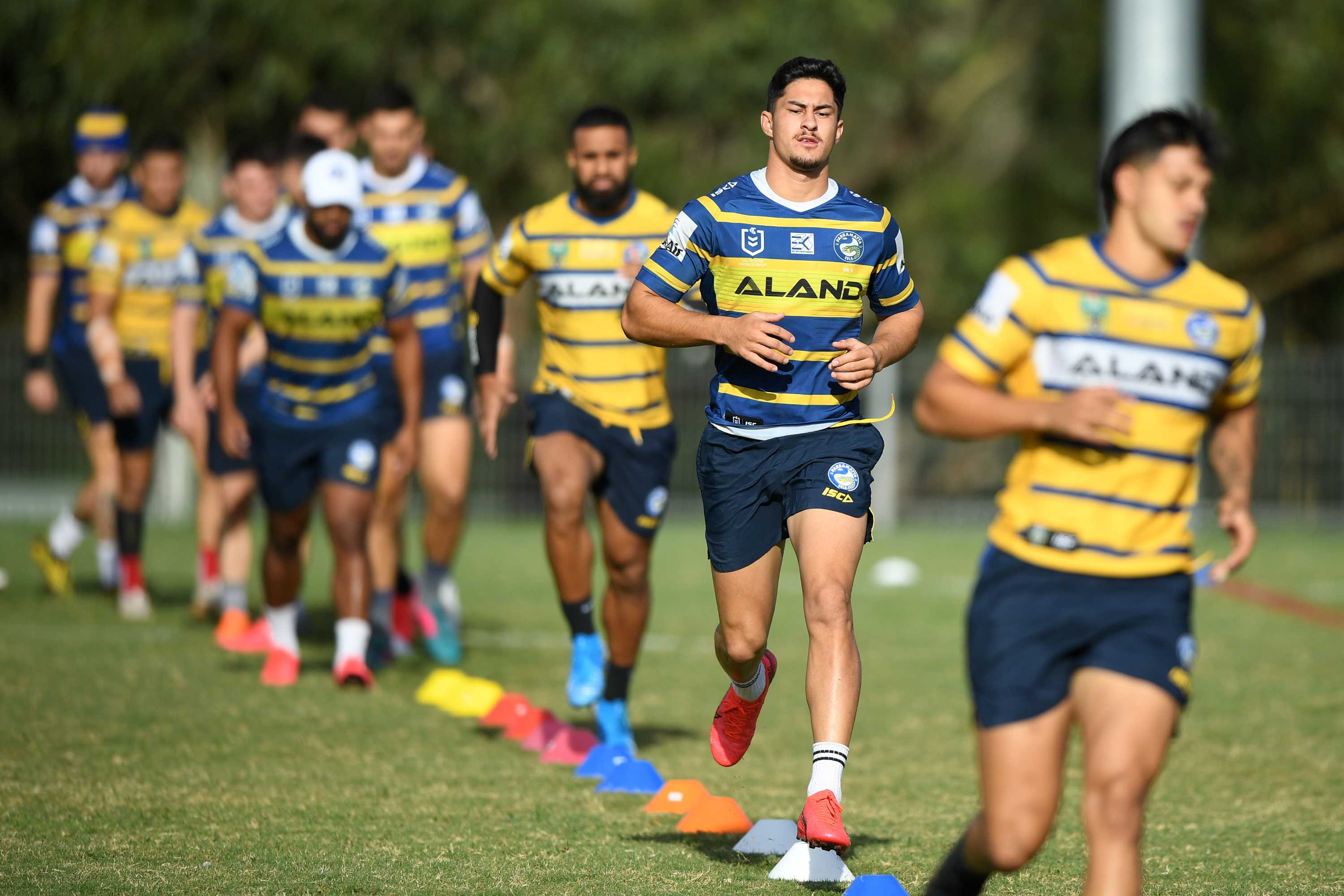 A Parramatta Eels NRL player runs behind and in front of his teammates at a training session.