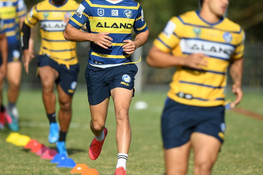 A Parramatta Eels NRL player runs behind and in front of his teammates at a training session.