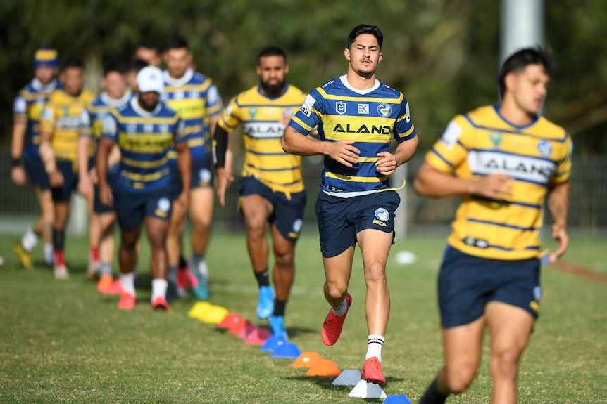 A Parramatta Eels NRL player runs behind and in front of his teammates at a training session.