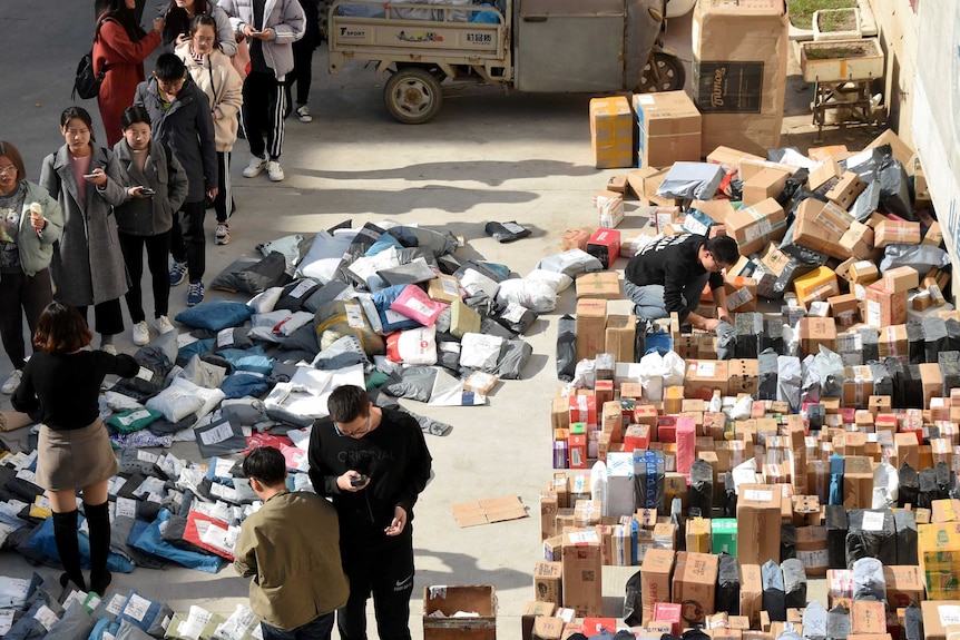 People queue up with lots of boxes on the side of a road