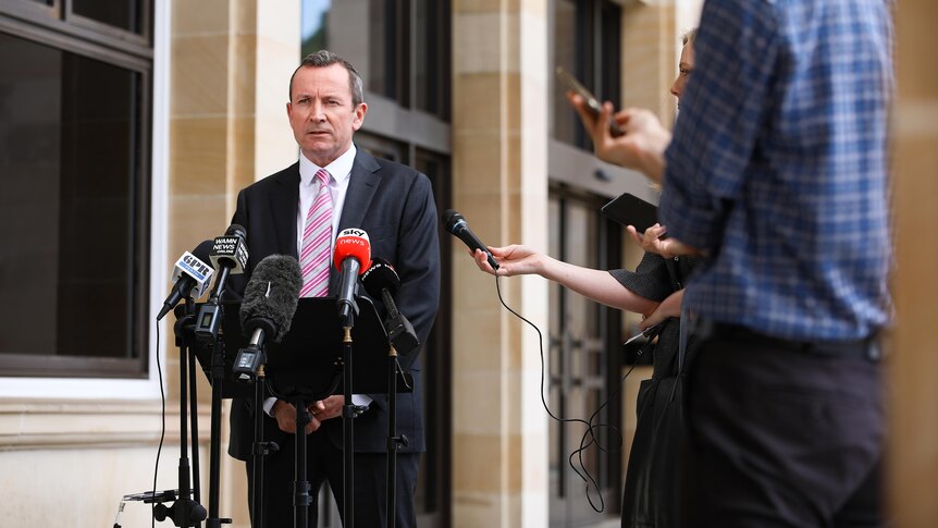 A wide shot of WA Premier Mark McGowan speaking outside state parliament, with reporters on his left.