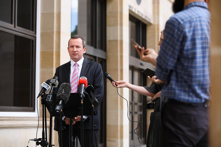 A wide shot of WA Premier Mark McGowan speaking outside state parliament, with reporters on his left.
