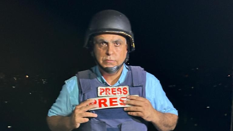 A man in a flack jacket and helmet with the sign "free press" on his chest