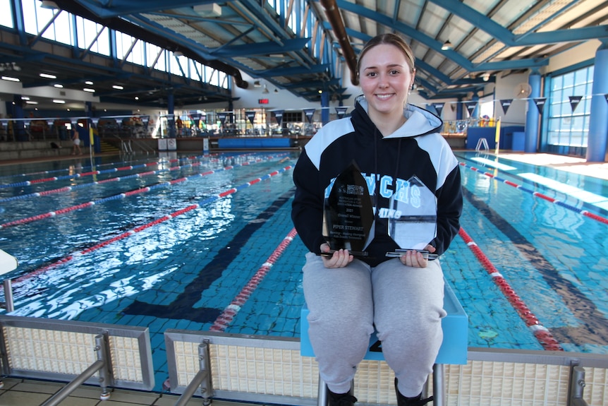 A woman at a pool with an award.