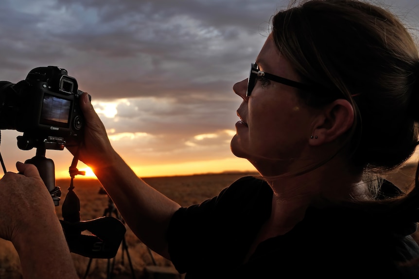 Kylie looking at the back of her camera as a storm brews in the distance