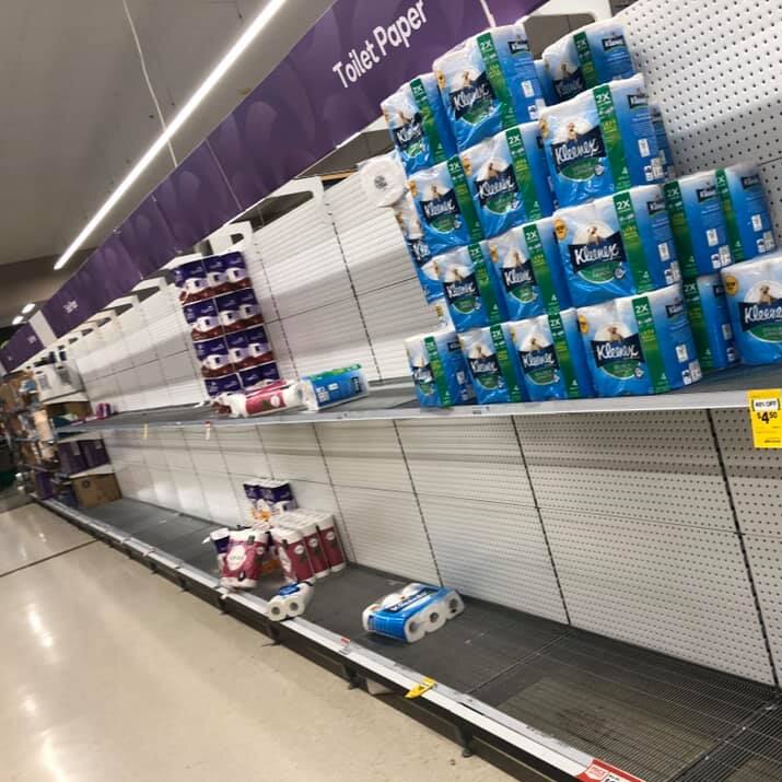 An aisle in Woolworths supermarket with mostly empty shelves labelled Toilet Paper