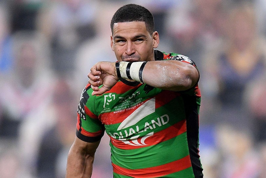 A South Sydney NRL player kisses the taping on his left wrist as he celebrates a try.