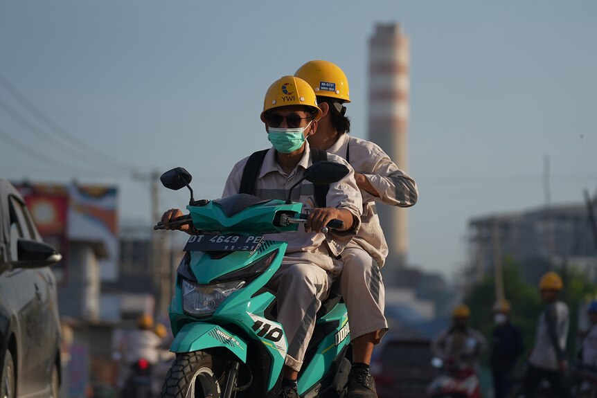 Two workers on a motorbike.