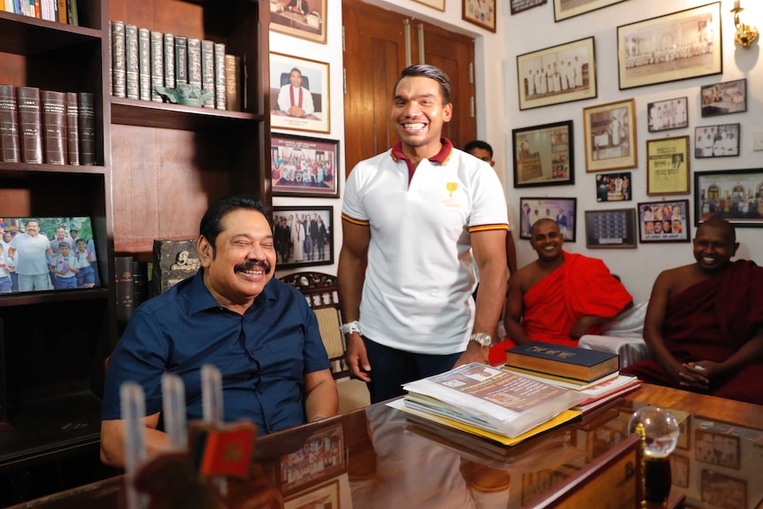 Sri Lankan Prime Minister Mahinda Rajapaksa sits for photographs, with his lawmaker son Namal by his side.