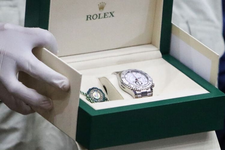 Gloved hands present a box containing a confiscated Rolex watch